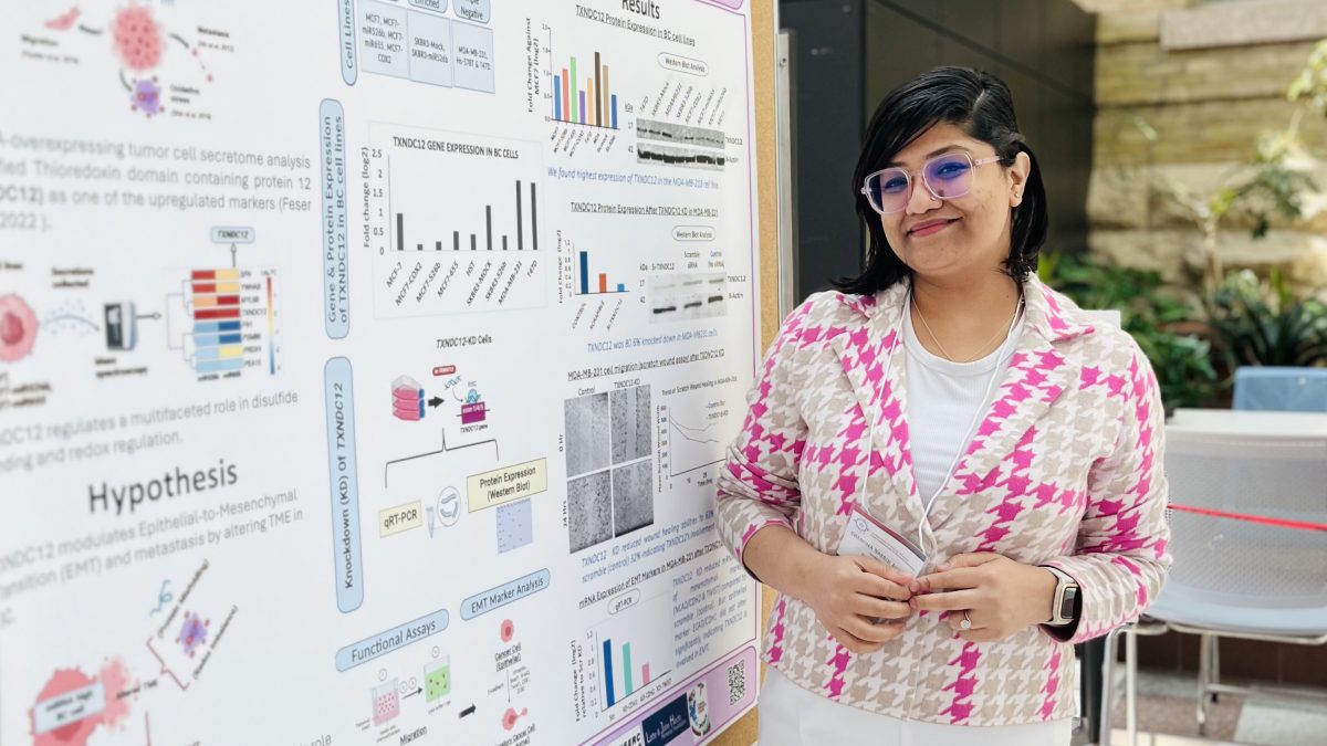 A woman smiles next to an academic poster