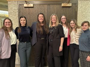 A group of seven people stand shoulder-to-shoulder in a group portrait.