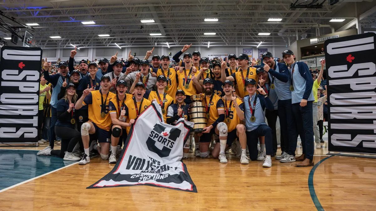 A group of men celebrate while holding up a trophy and a banner