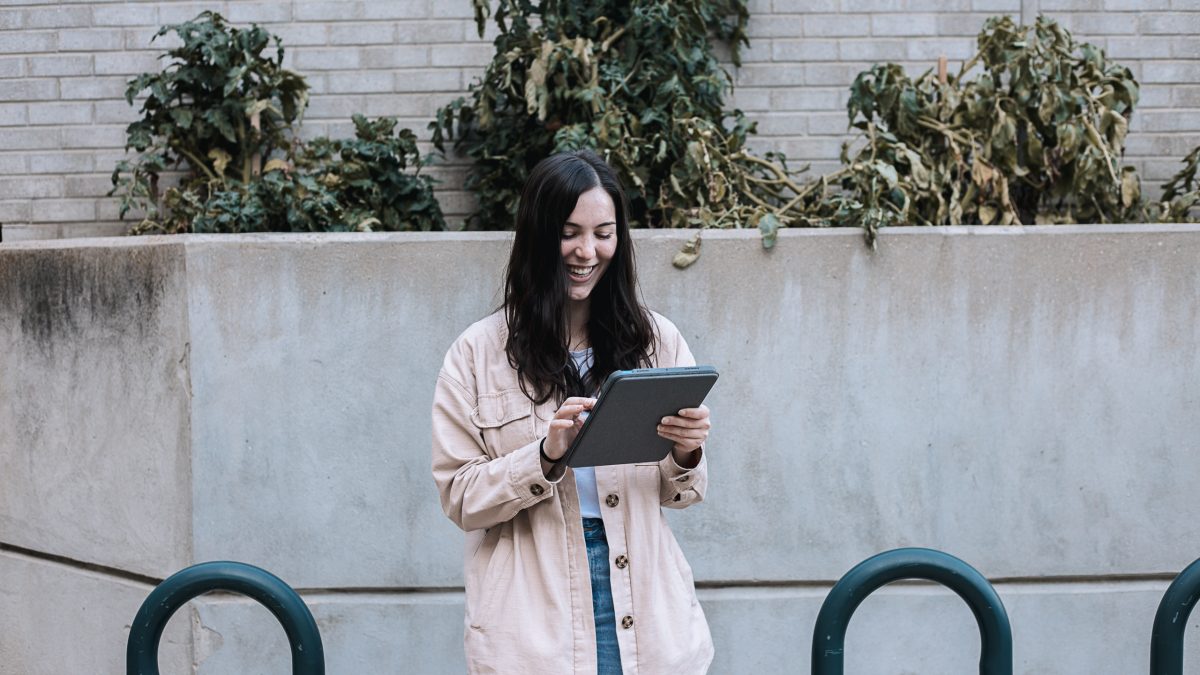 A woman smiles as she uses a tablet