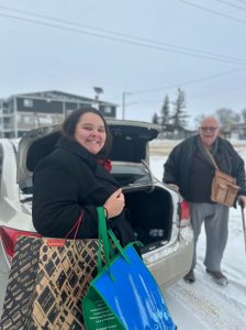 Young woman loads trunk of a vehicle with an older man.