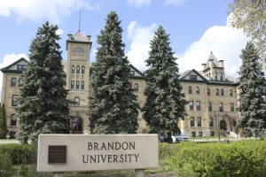 Historic Clark Hall and the Brandon College original building, with a 'Brandon University' sign in front.