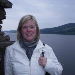 A woman smiles in front of a body of water