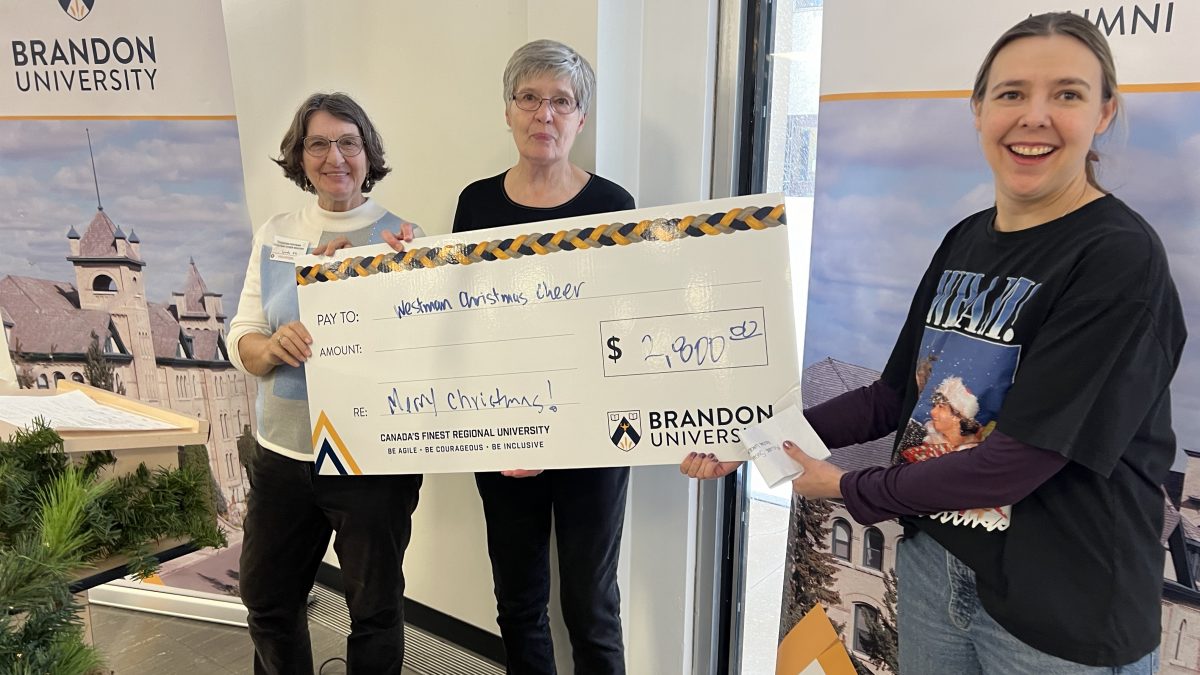 Three women pose with an oversize novelty cheque.