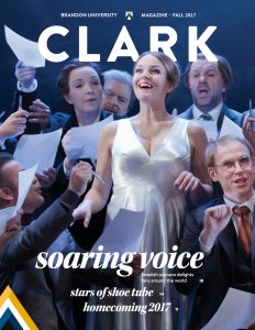 Cover of Clark Magazine, features a photo of opera singer performing onstage surrounded by castmates