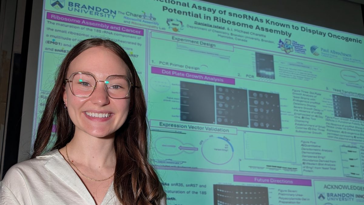 A woman smiles posing next to a research poster
