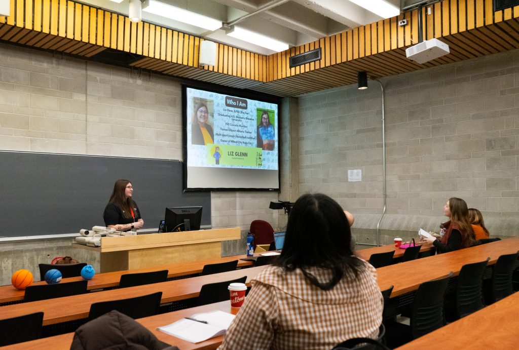 A person gives a presentation on a screen at the front of a lecture theatre.