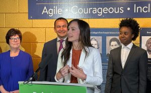 A woman gestures while speaking with three people behind her