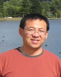 Dr. Li stands in front of a body of water
