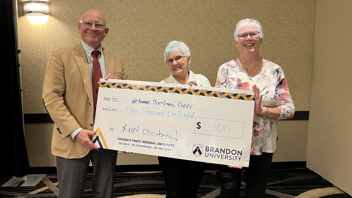 Three people stand with an oversized novelty cheque, showing more than $3,000 donated to Christmas Cheer.