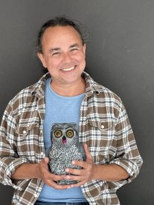 A man poses with an owl figurine