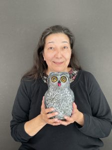 A woman poses with an owl figurine.