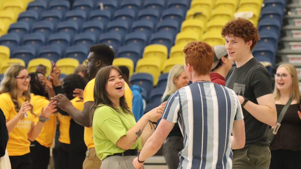 A woman laughs as she talks with two students
