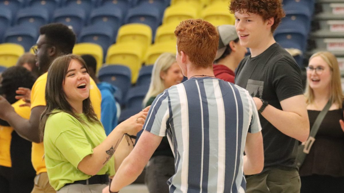 A woman laughs as she talks with two students