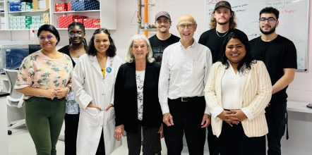 A large group of people stand in a laboratory