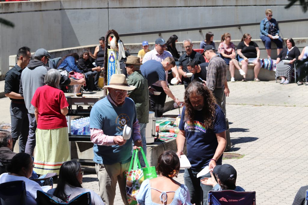 Two men hand out bowls and napkins