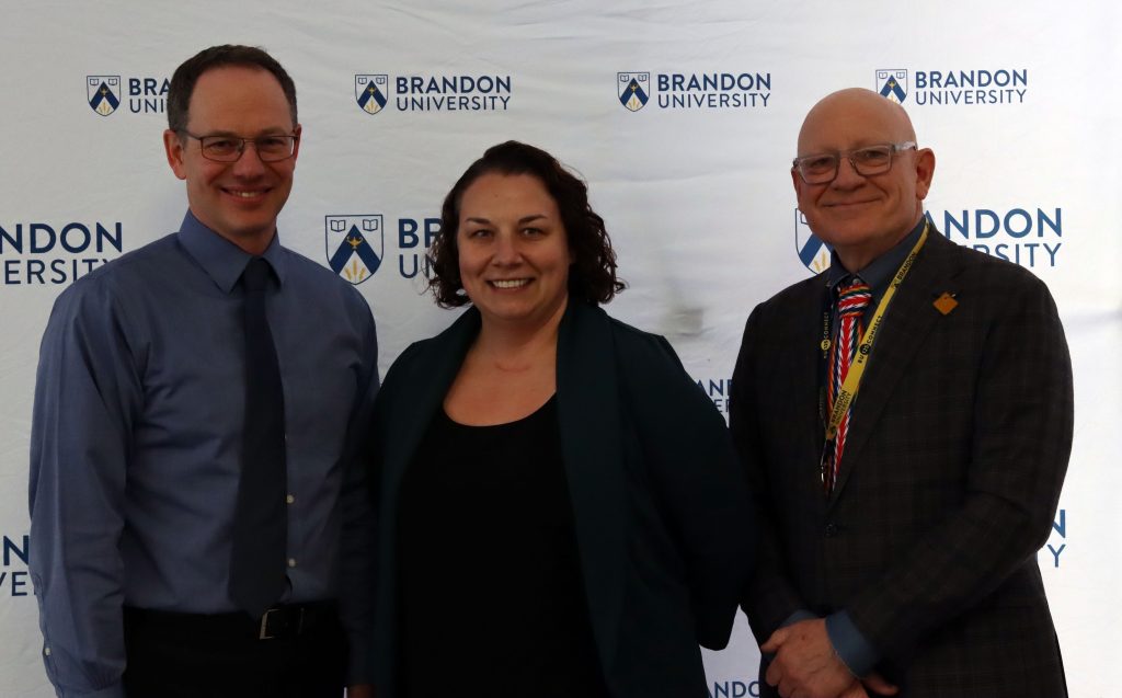 A woman poses between two men