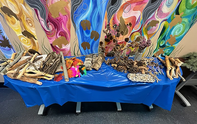 Various arrangements of sticks, branches, feathers and pinecones sit on a table with a blue tablecloth