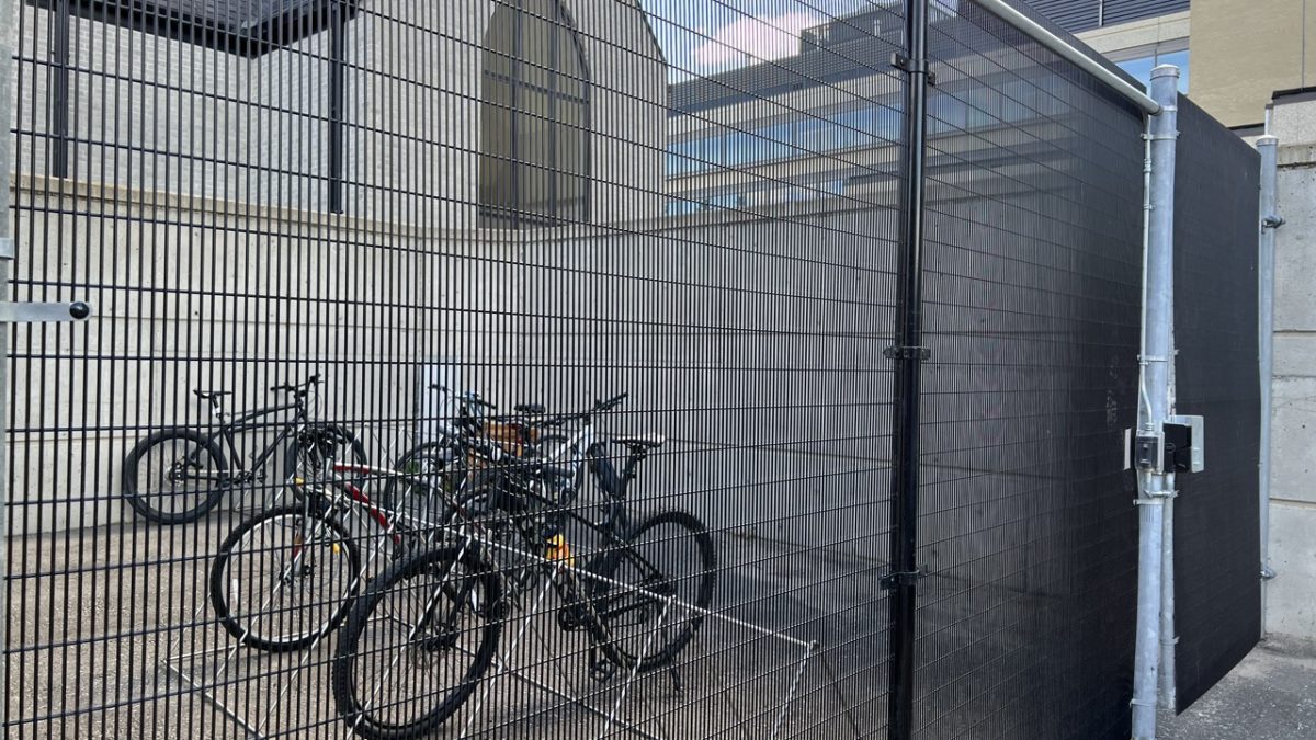 Bikes are stored behind a chain-link fence.