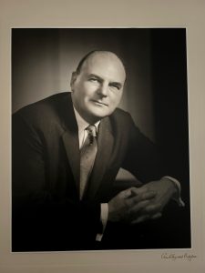 Black and white photo of a man in a suit with hands clasped