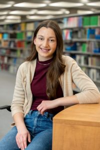 A young woman poses in a library.