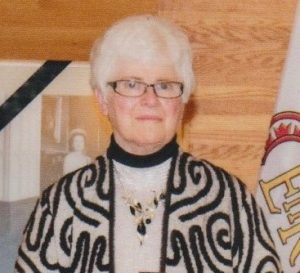 Portrait of a woman standing in front of a wood panel backdrop.