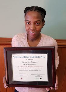 Thompson holds a framed certificate in front of her.