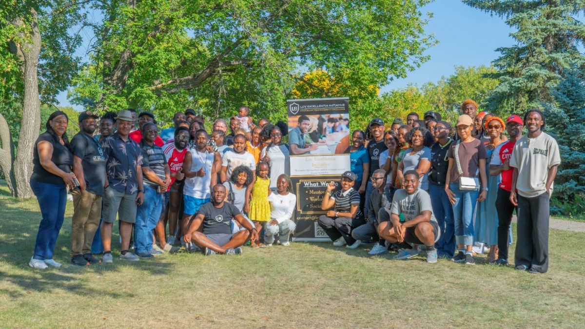 A large group of people pose in a field