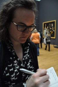 Woman in profile writing notes in a museum