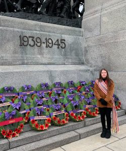 A woman stands in front of a World War II memorial and wreaths