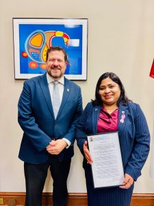 Two people pose with a framed statement.