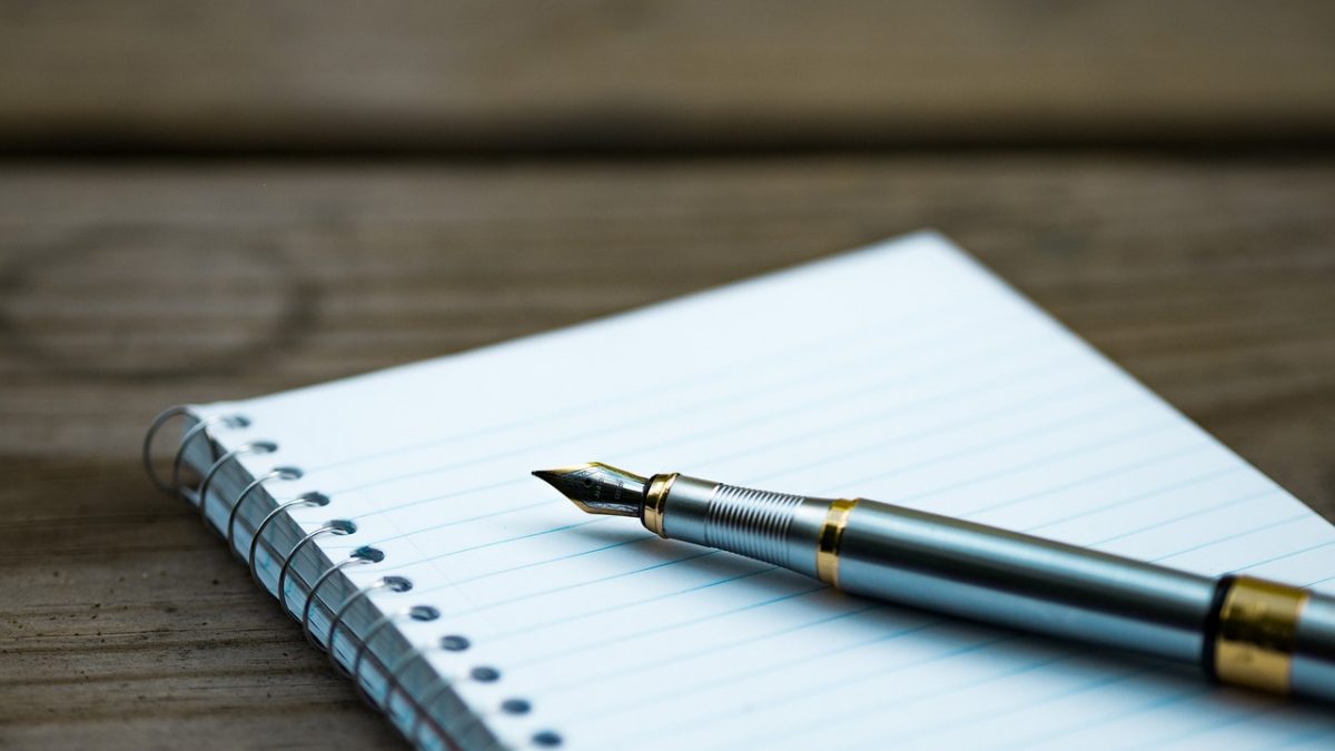 A fountain pen lies on a writing pad