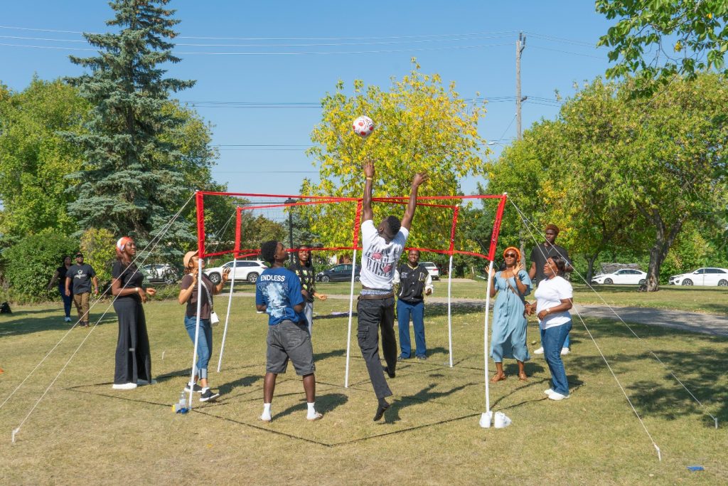 A group of people play four-square volleyball