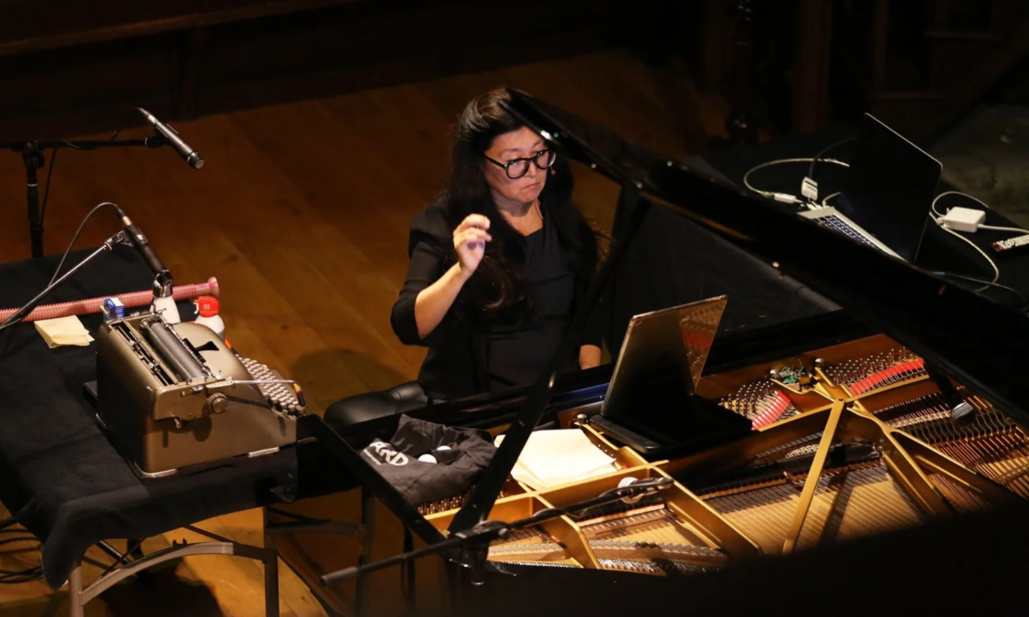A woman sits at a piano