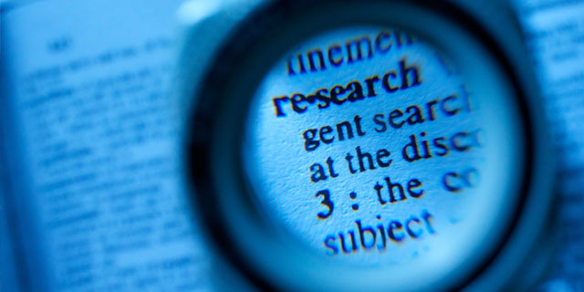 A magnifying glass highlights a definition of research